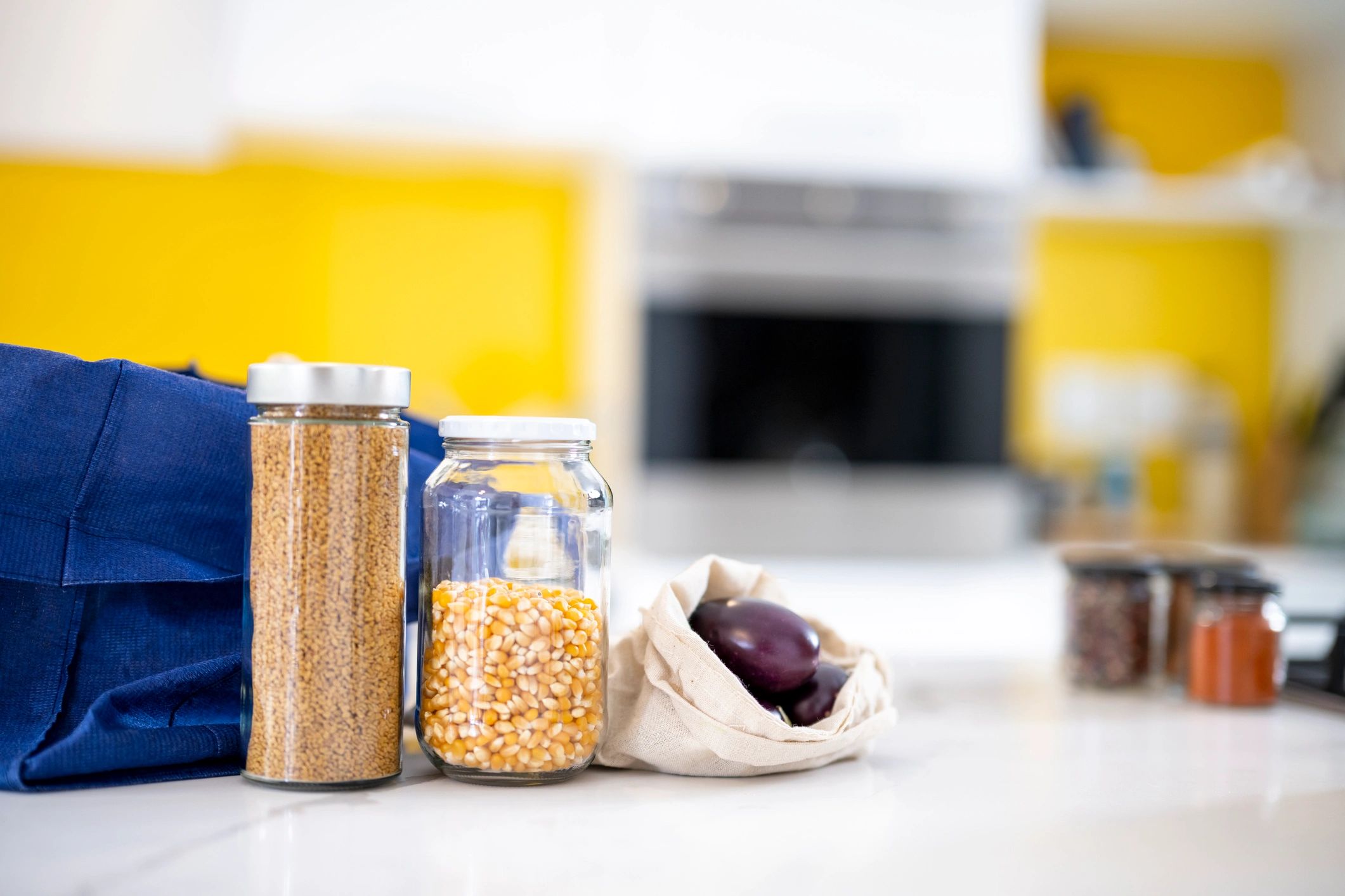 Reused glass jars with seeds and cotton vegetable bags with aubergine