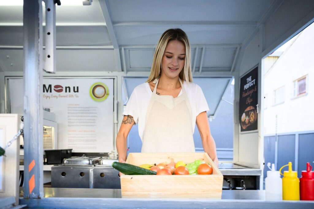 Young woman with box of organic vegetables in food truck
