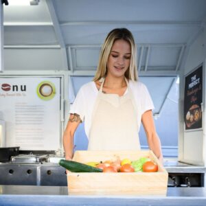 Young woman with box of organic vegetables in food truck