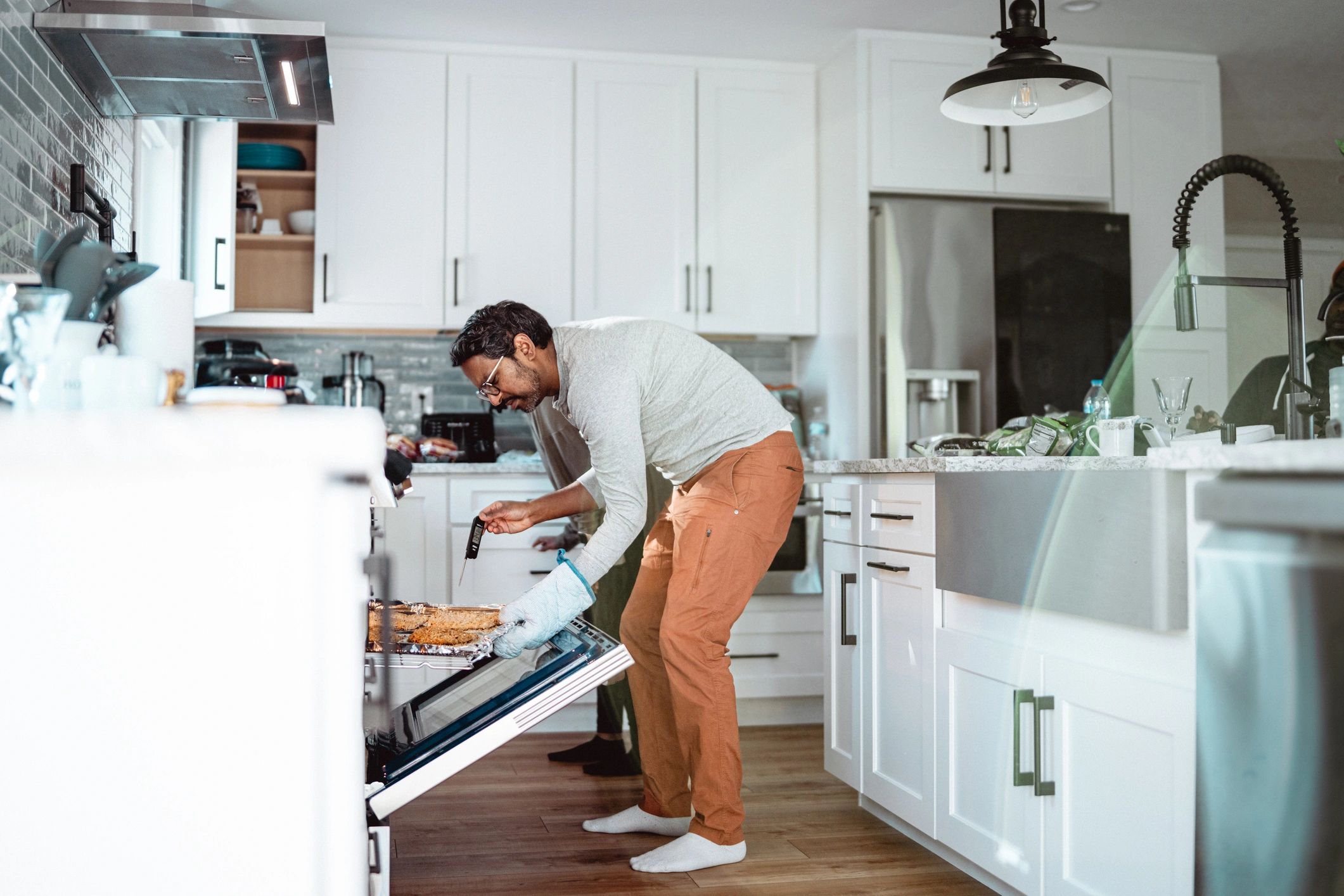Man checking temperature of chicken baking in oven