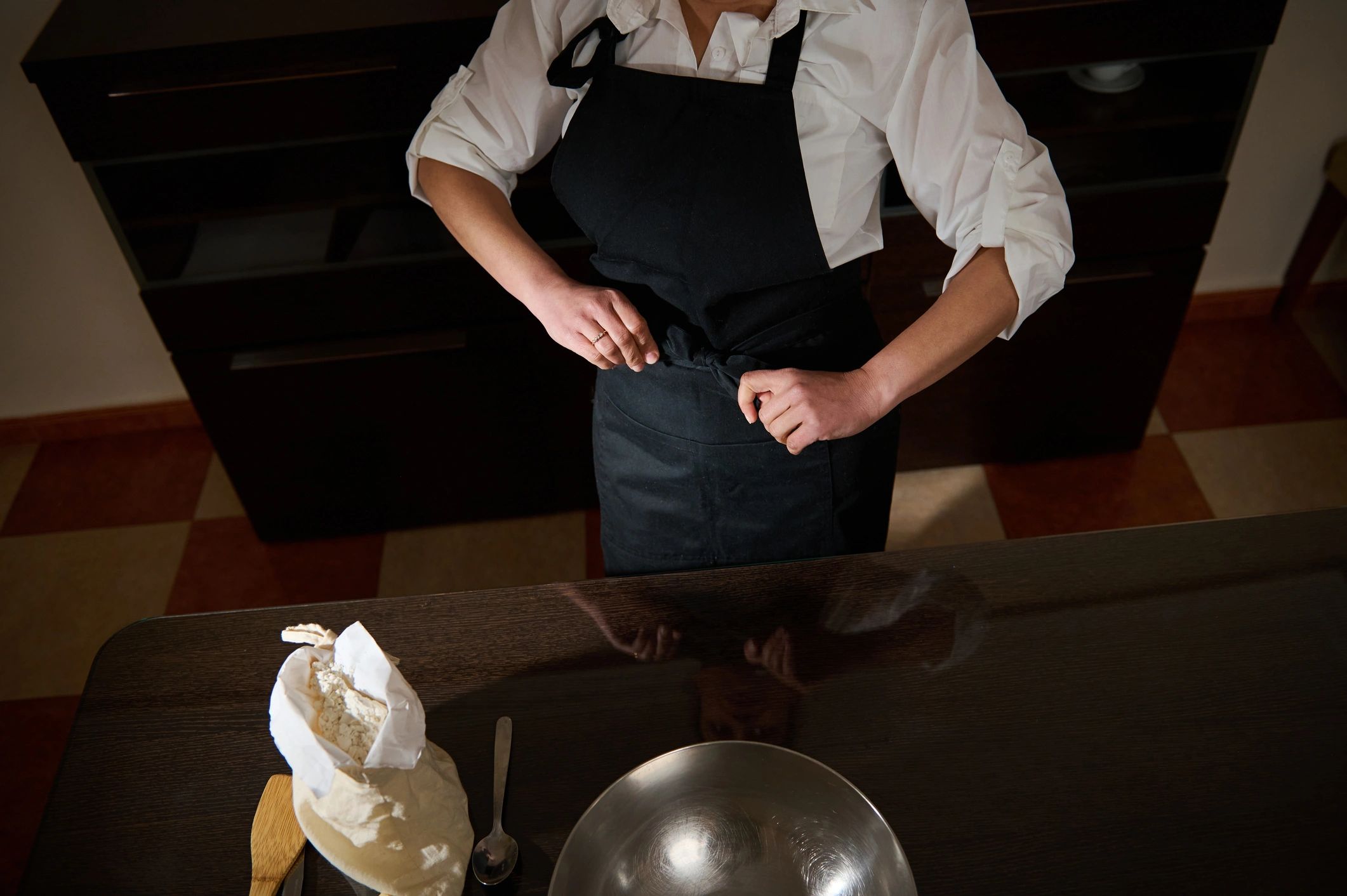 Pastry chef tying apron in kitchen